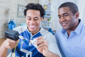 African American father and son bond while working on robotics project