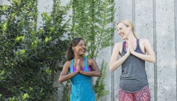 Two multi-ethnic women practicing yoga, smiling