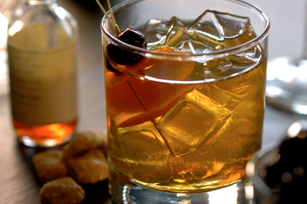 Cocktail on the Rocks With Brown Liquor, Cherry and Sugar Cube