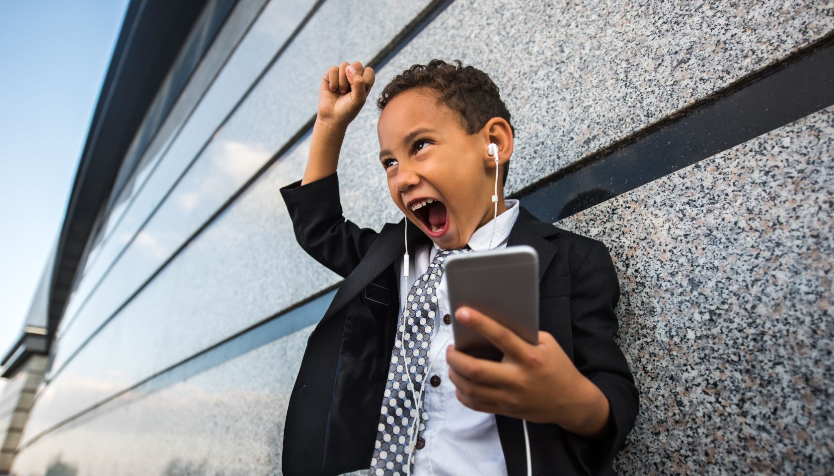 Cheerful African American business boy singing while listening MP3 player.