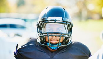 Medium shot portrait of boy in football gear before game on fall afternoon