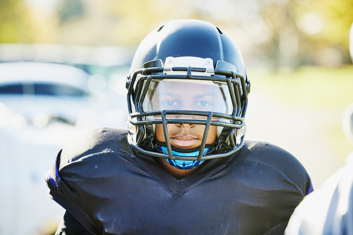 Medium shot portrait of boy in football gear before game on fall afternoon