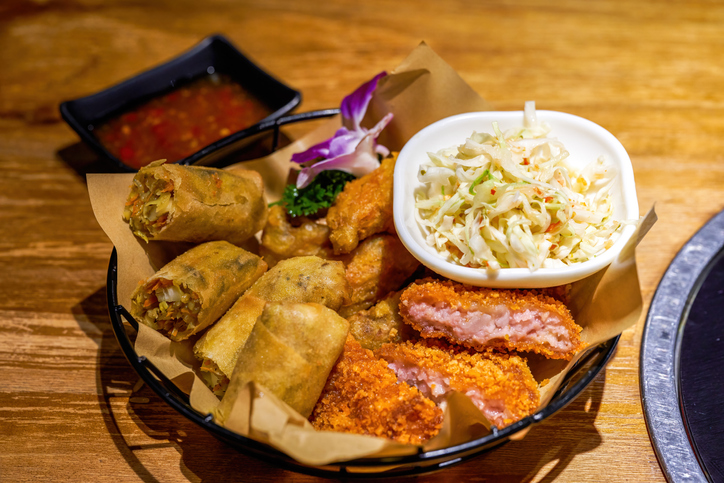 A plate of Thai snacks, fried shrimp cakes, fried spring rolls and vegetable salad