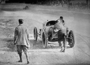 Race car driver Ralph DePalma and his riding mechanic, Rupert Jeffkins, pushing their car towards the finish line at the 1912 Indianapolis 500 automobile race