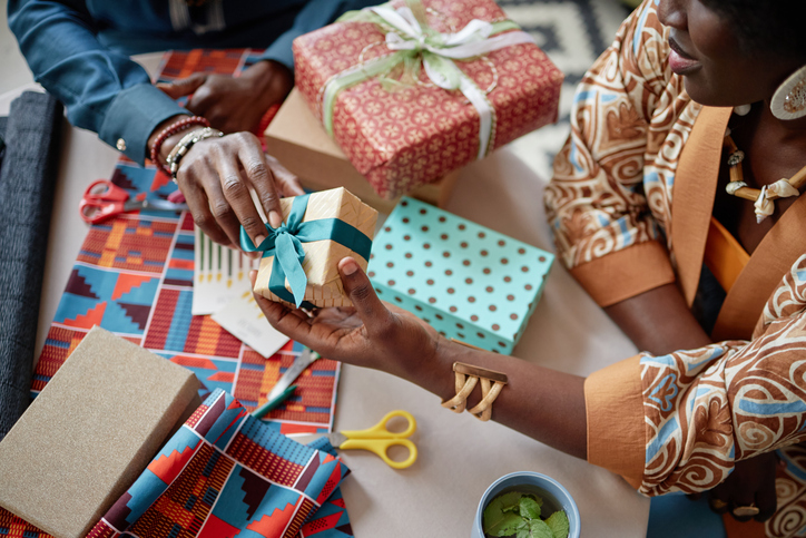 Black Woman and Black Man Exchanging Wrapped Gifts during Kwanzaa Celebration