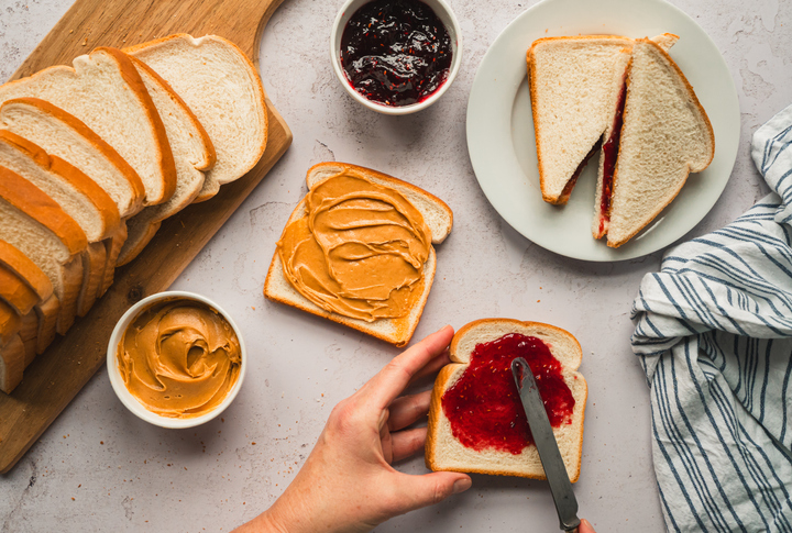 Top view peanut and butter jam sandwiches being made on white counter