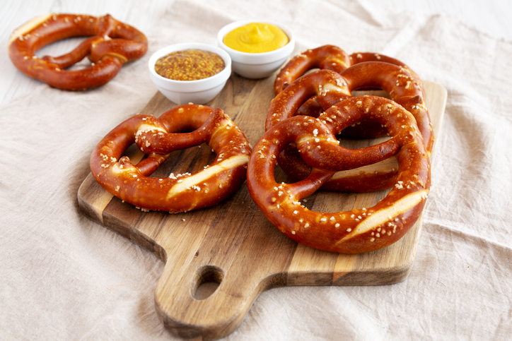 Homemade Soft Bavarian Pretzels with Mustard on a wooden board, side view.