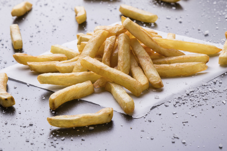 Fresh yellow fries on a black table with sea salt