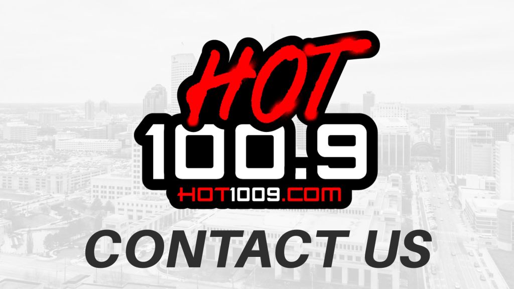 Hot 100.9 logo and "Contact Us" text against a cityscape background.